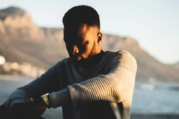 Troubled man sitting near the sea at sunrise