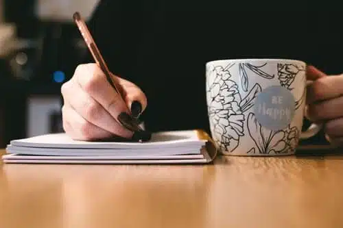Writing on a notebook while having coffee
