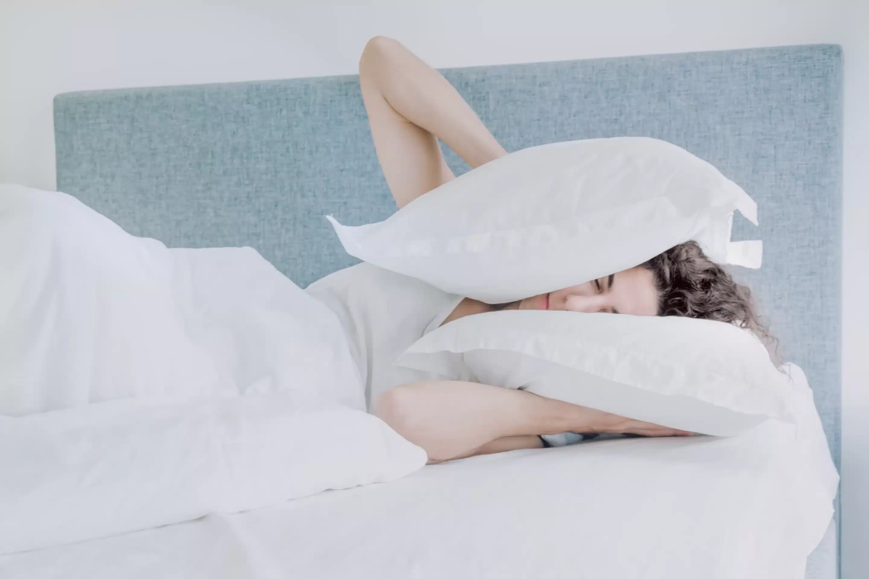 a person lying in bed with pillows covering their face
