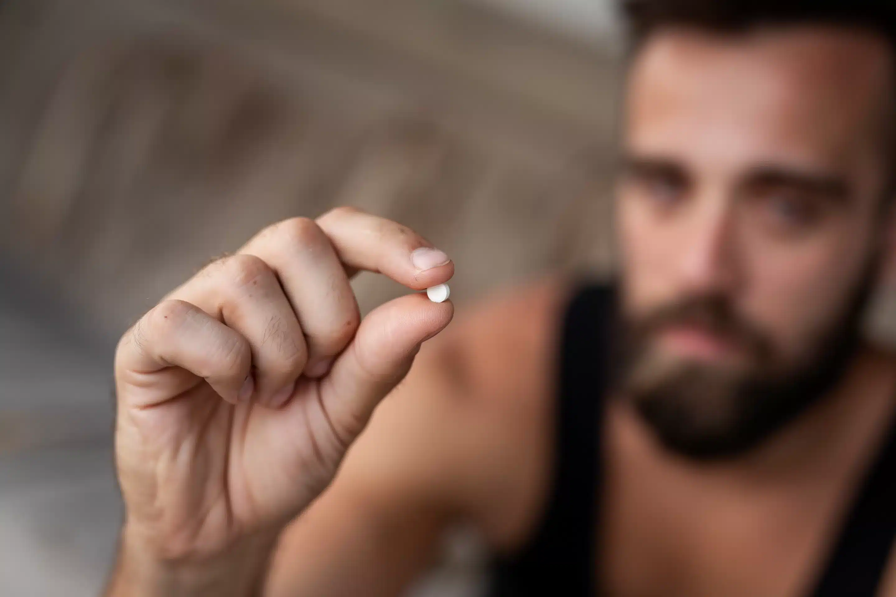 Man holding an ecstasy pill. Focus on the pill