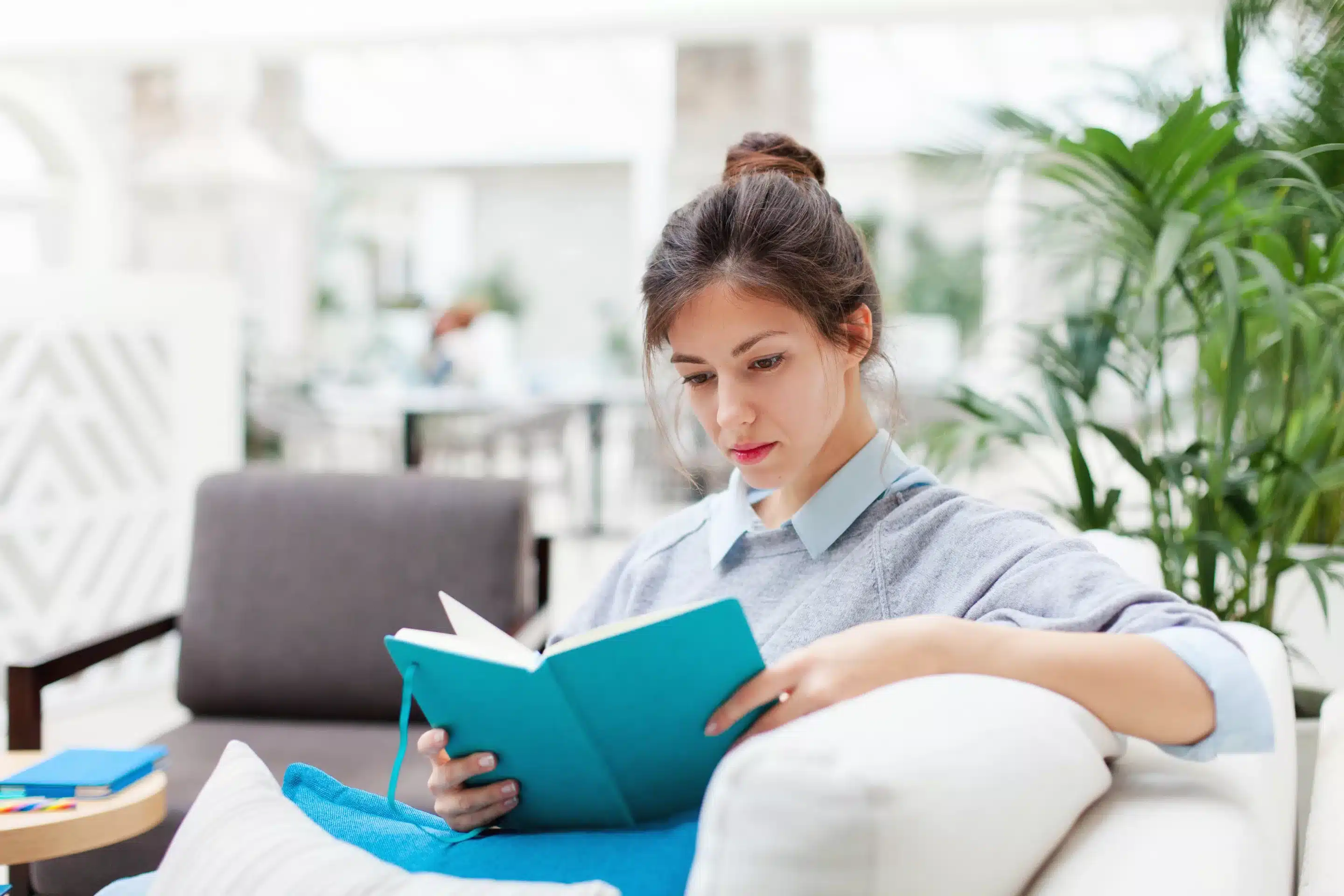 woman sitting on sofa with an open book
