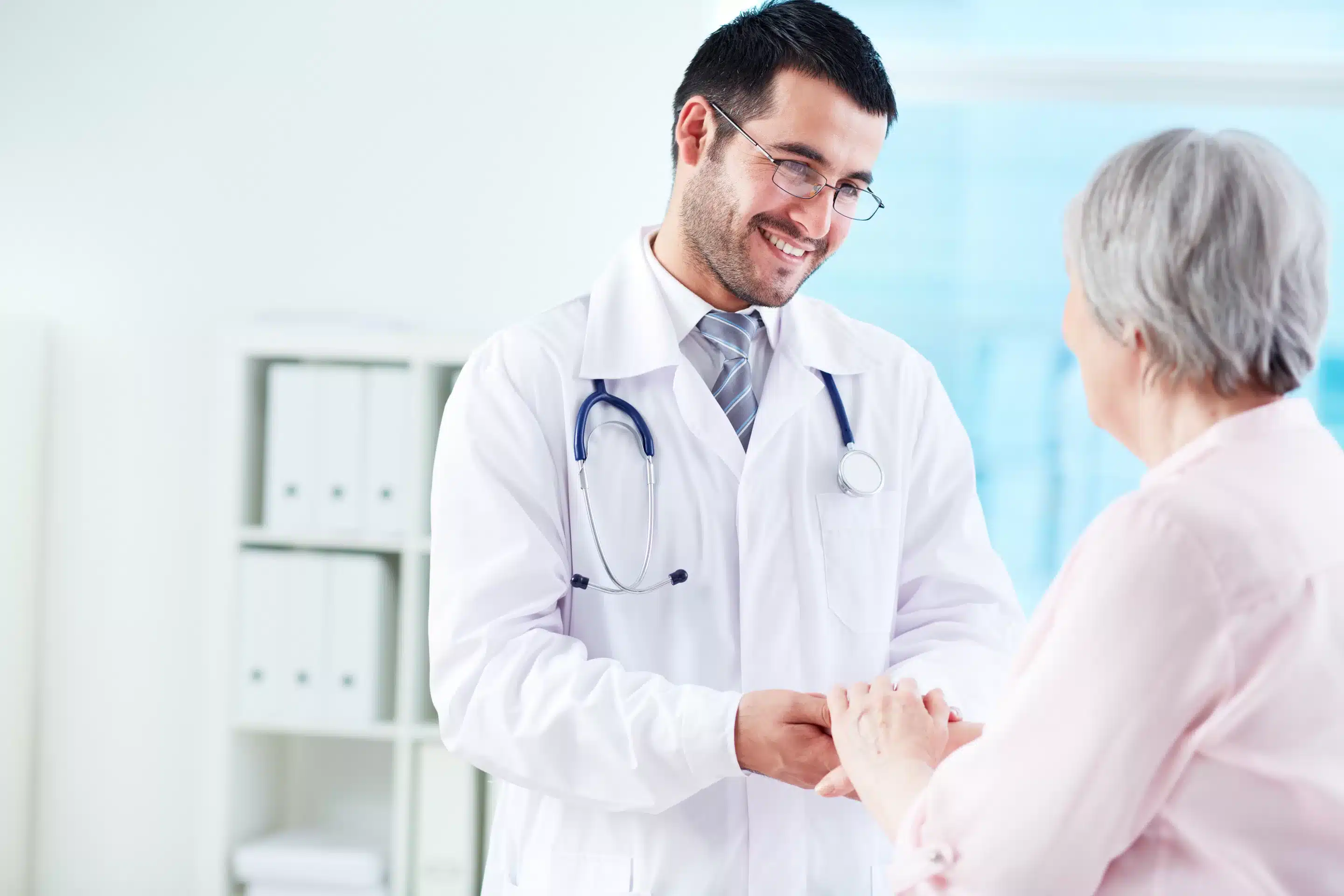 Confident doctor looking at his senior patient while speaking to he