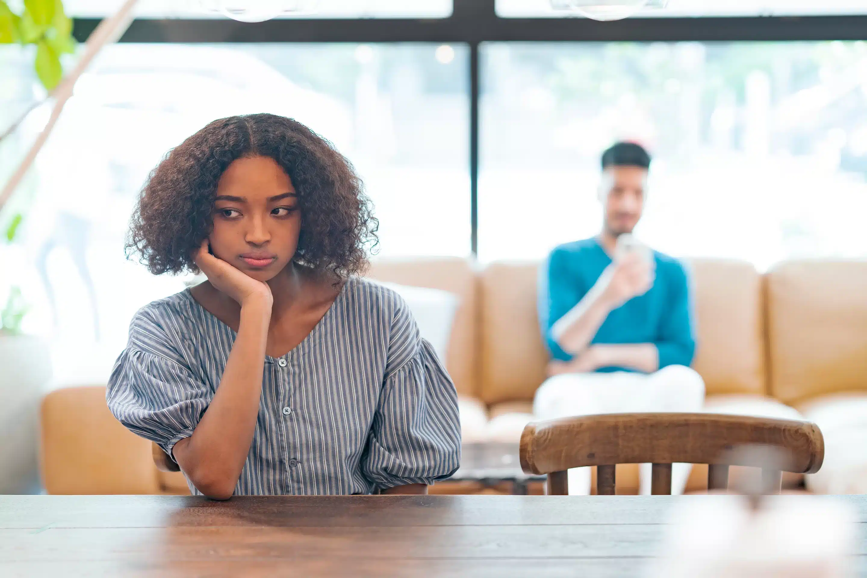 a woman sitting at a table with her hand on her chin