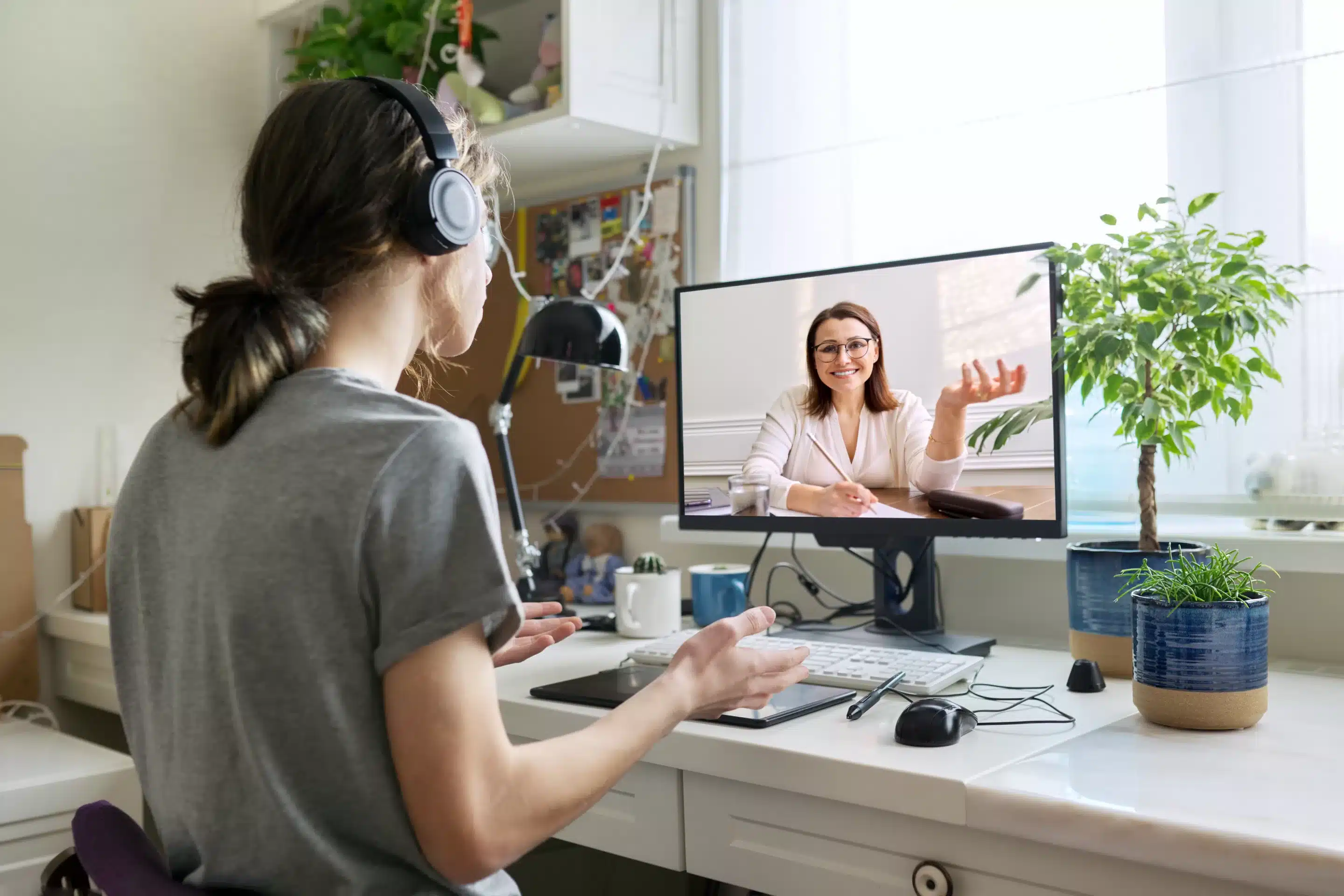 a woman wearing headphones and talking to a woman on a computer