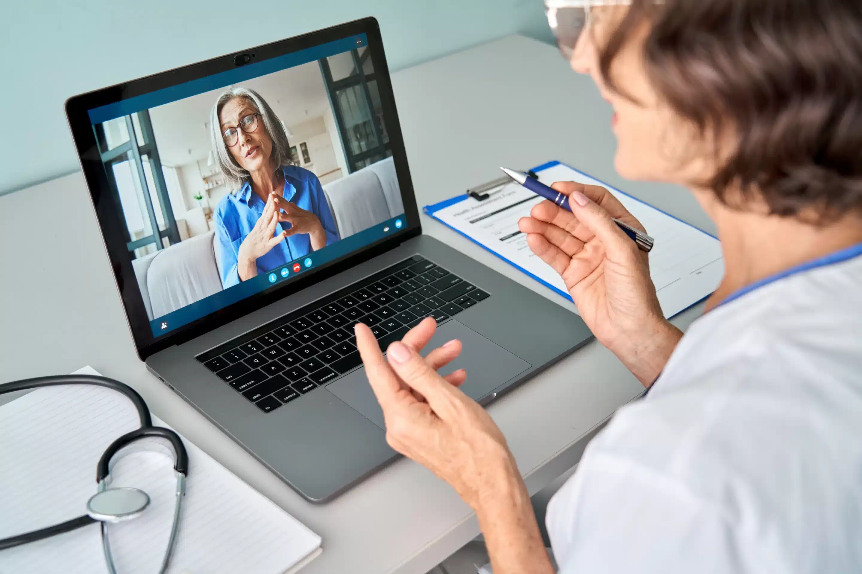 person sitting while using laptop computer and green stethoscope near