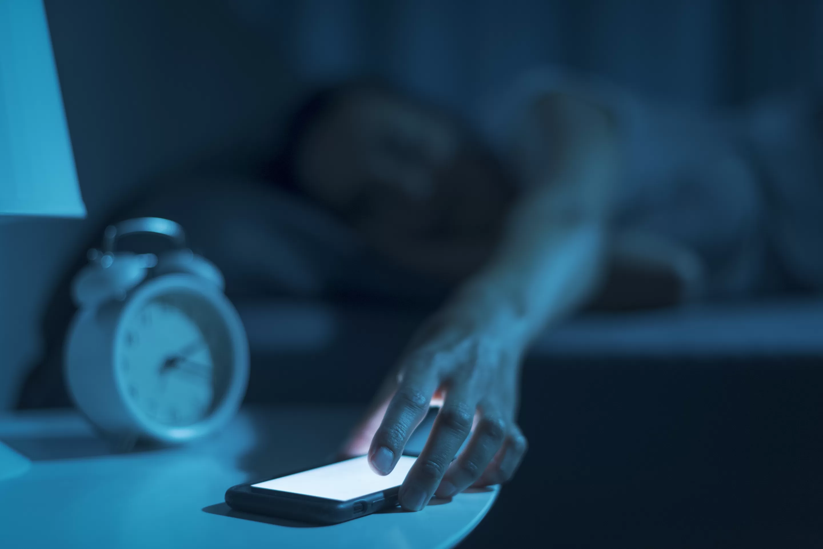 Sleep Hygiene a person lying down in bed with a phone