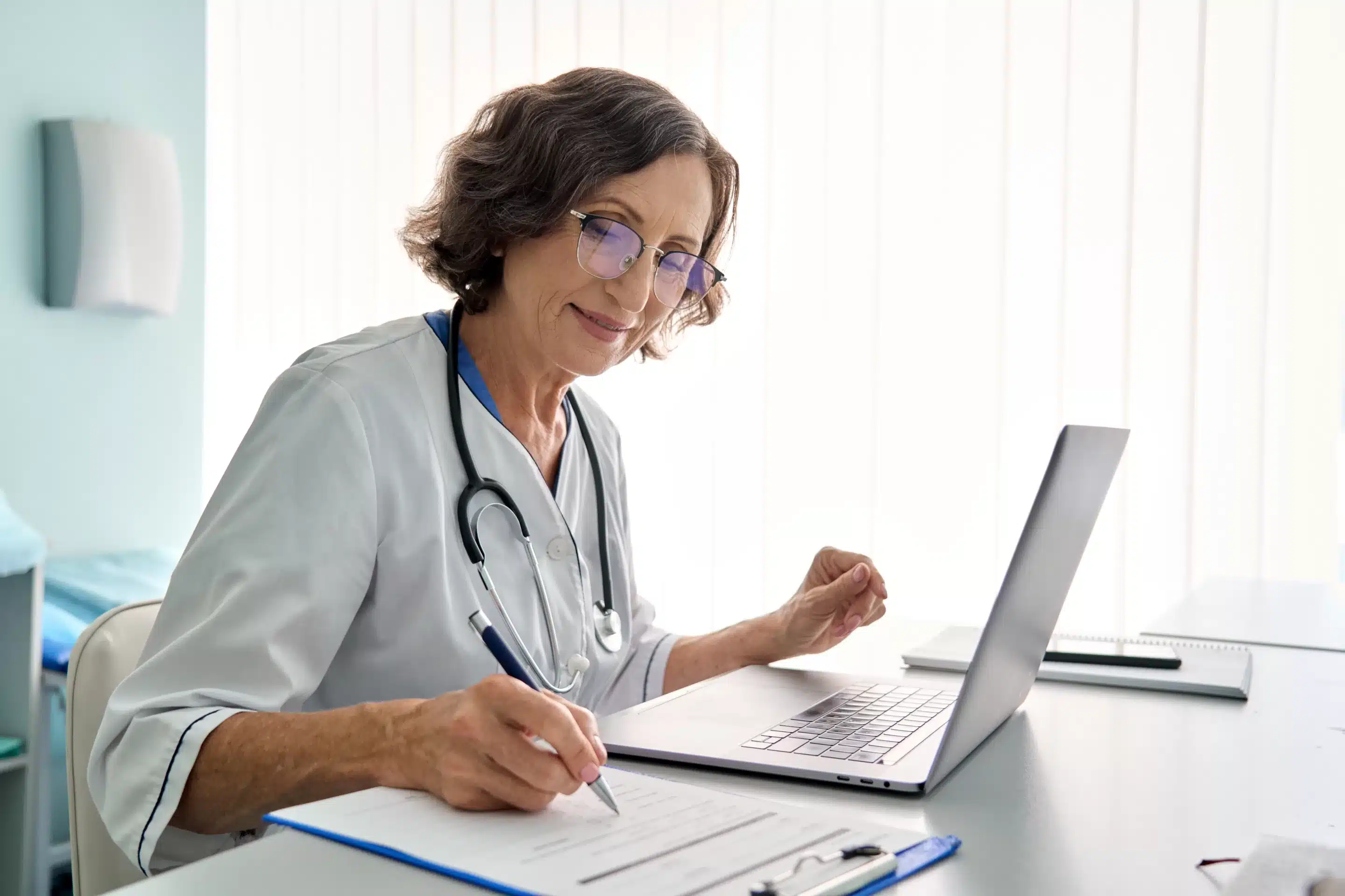 person sitting while using laptop computer and green stethoscope near