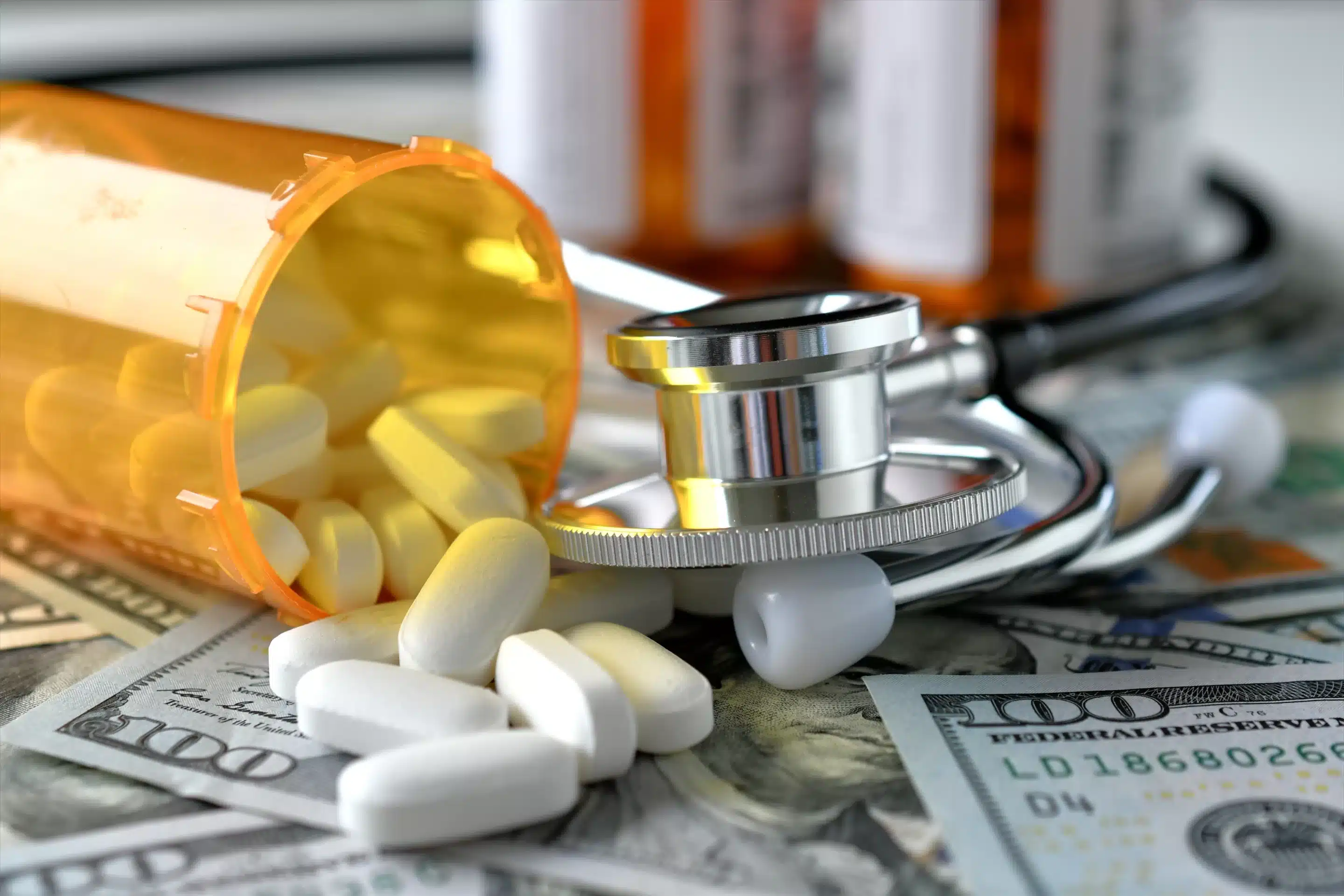 Stethoscope laying on medicine white pills money with RX prescription drug bottle