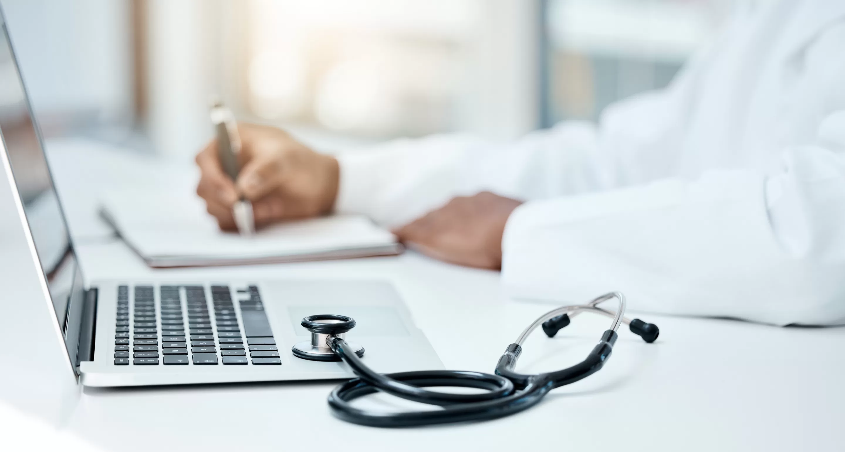 person sitting while using laptop computer and green stethoscope near