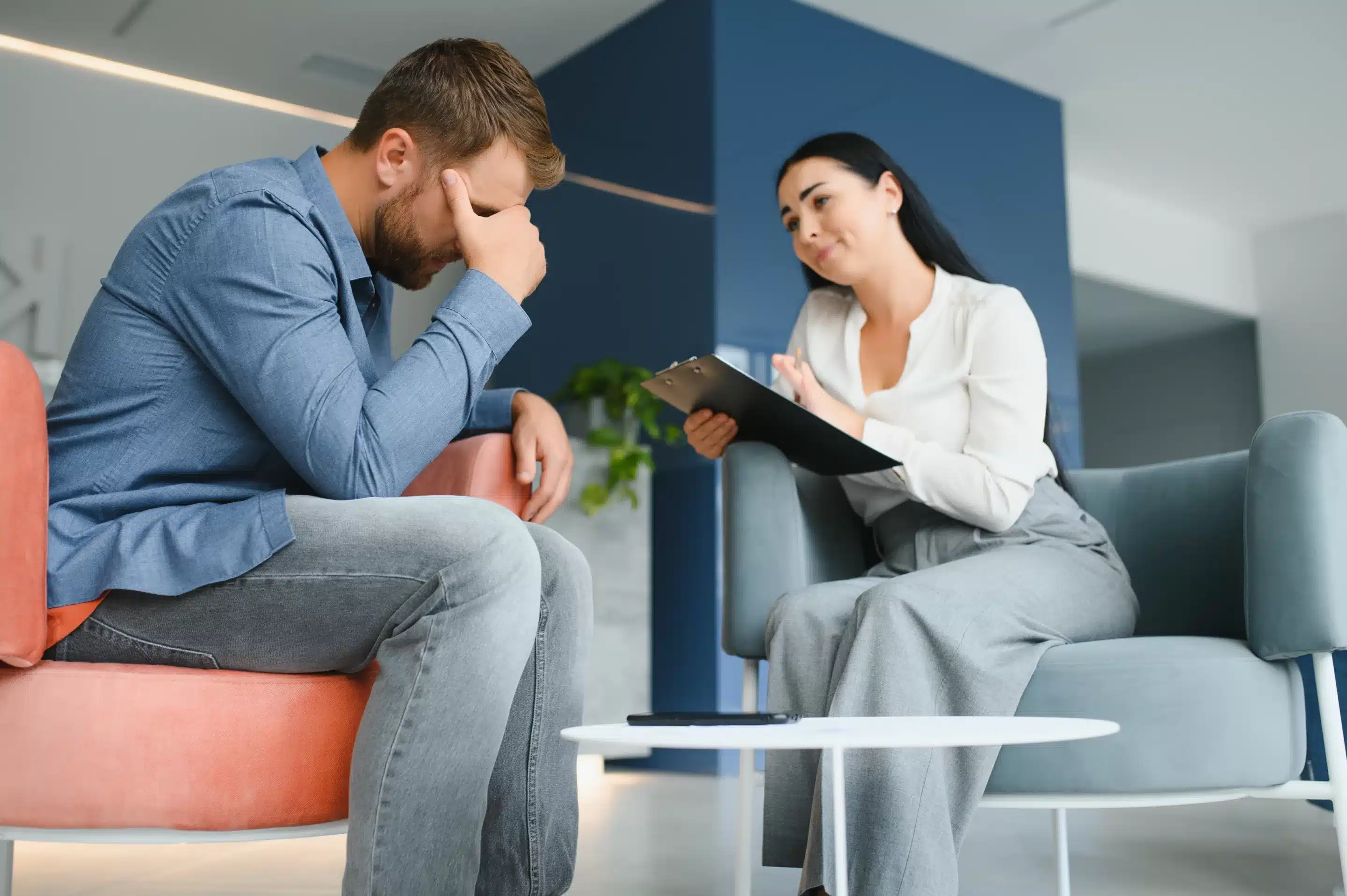 Upset man alcoholic sitting at psychologist on psychotherapy session, sad depressed