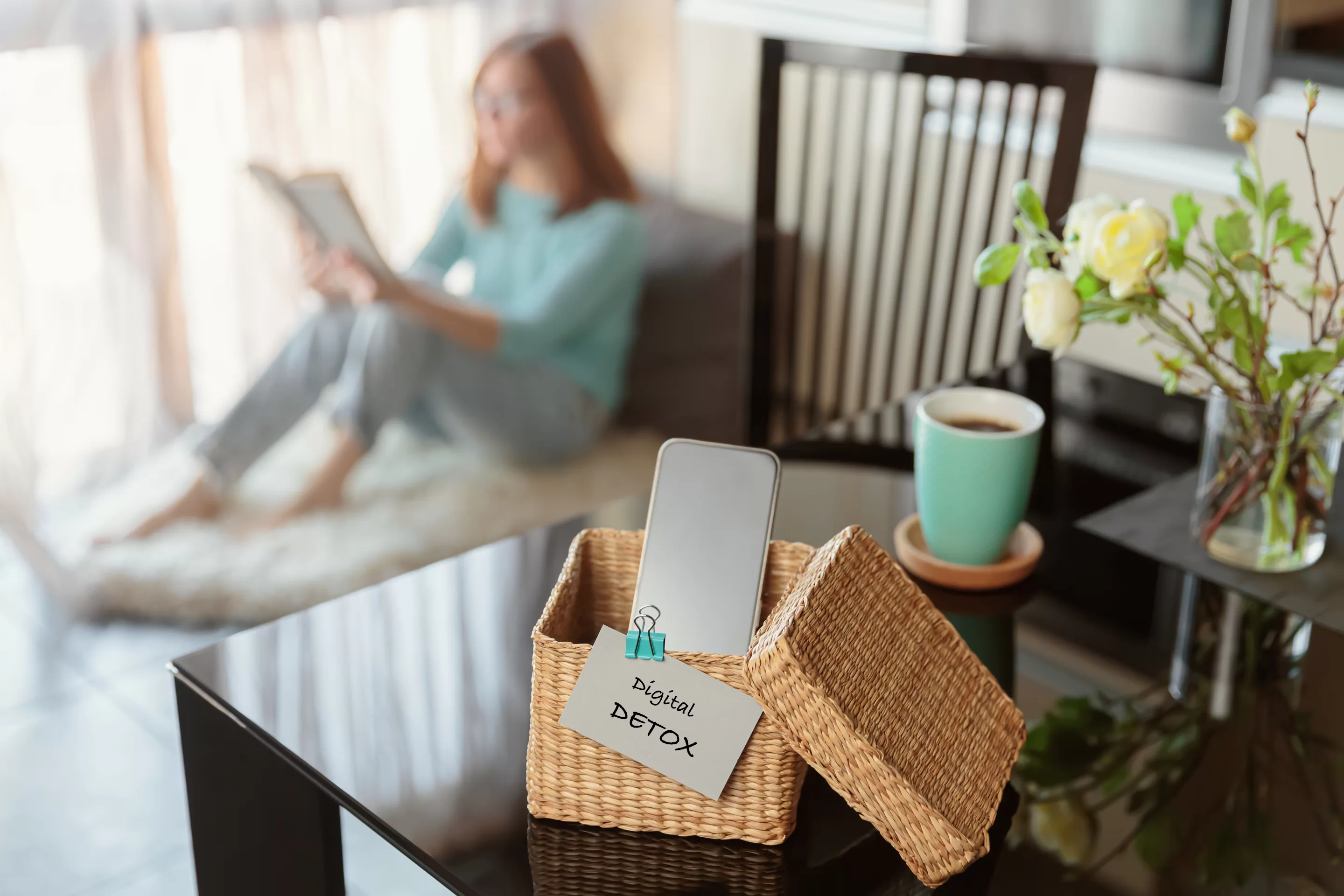 Smartphone is in separate wicker box with inscription digital detox on table.