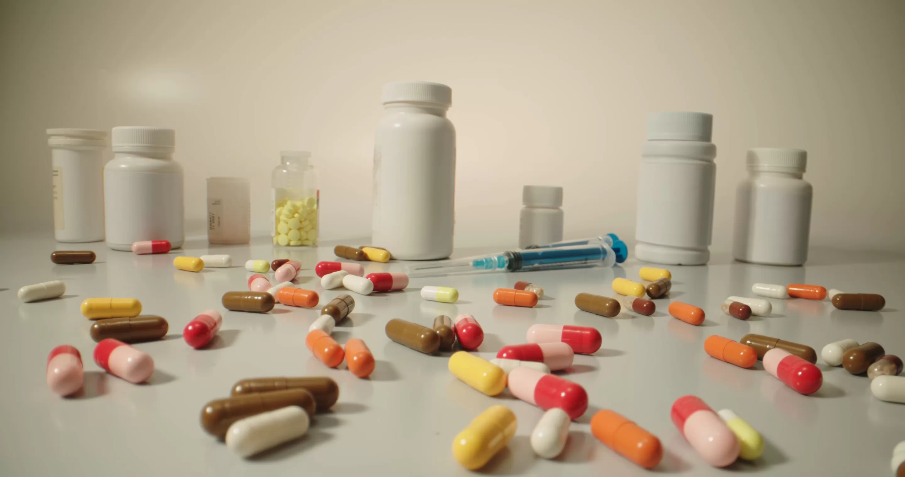 Colorful pills and tablets falling on white table with different types of drugs
