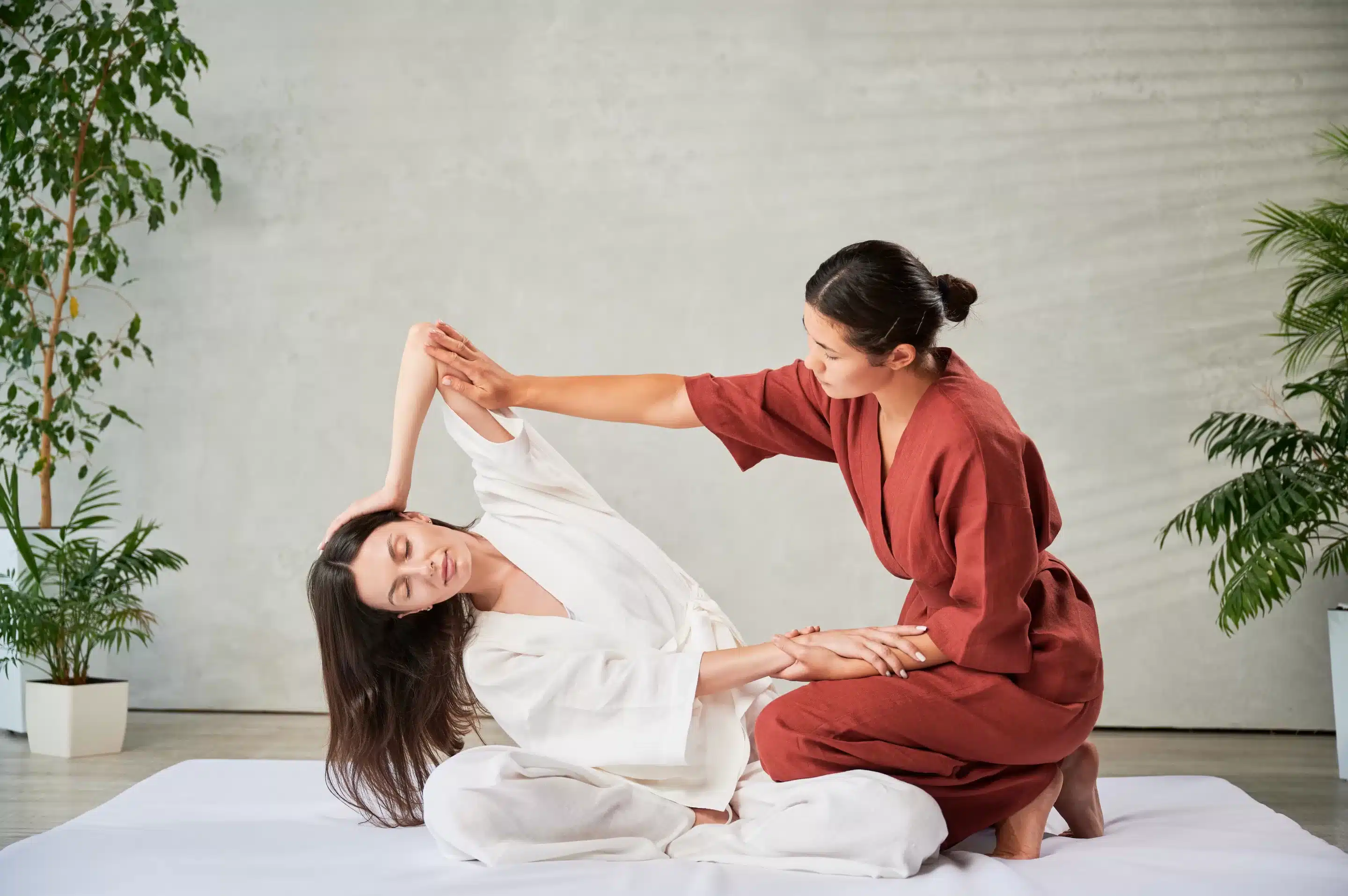Masseuse making thai yoga massage. Woman therapist doing traditional massage treatment