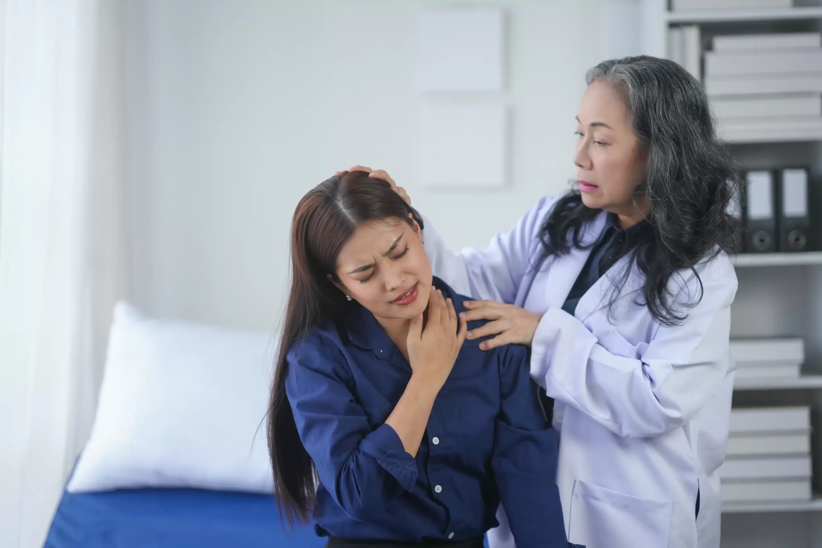Doctor examining a patient's neck pain in a medical office.