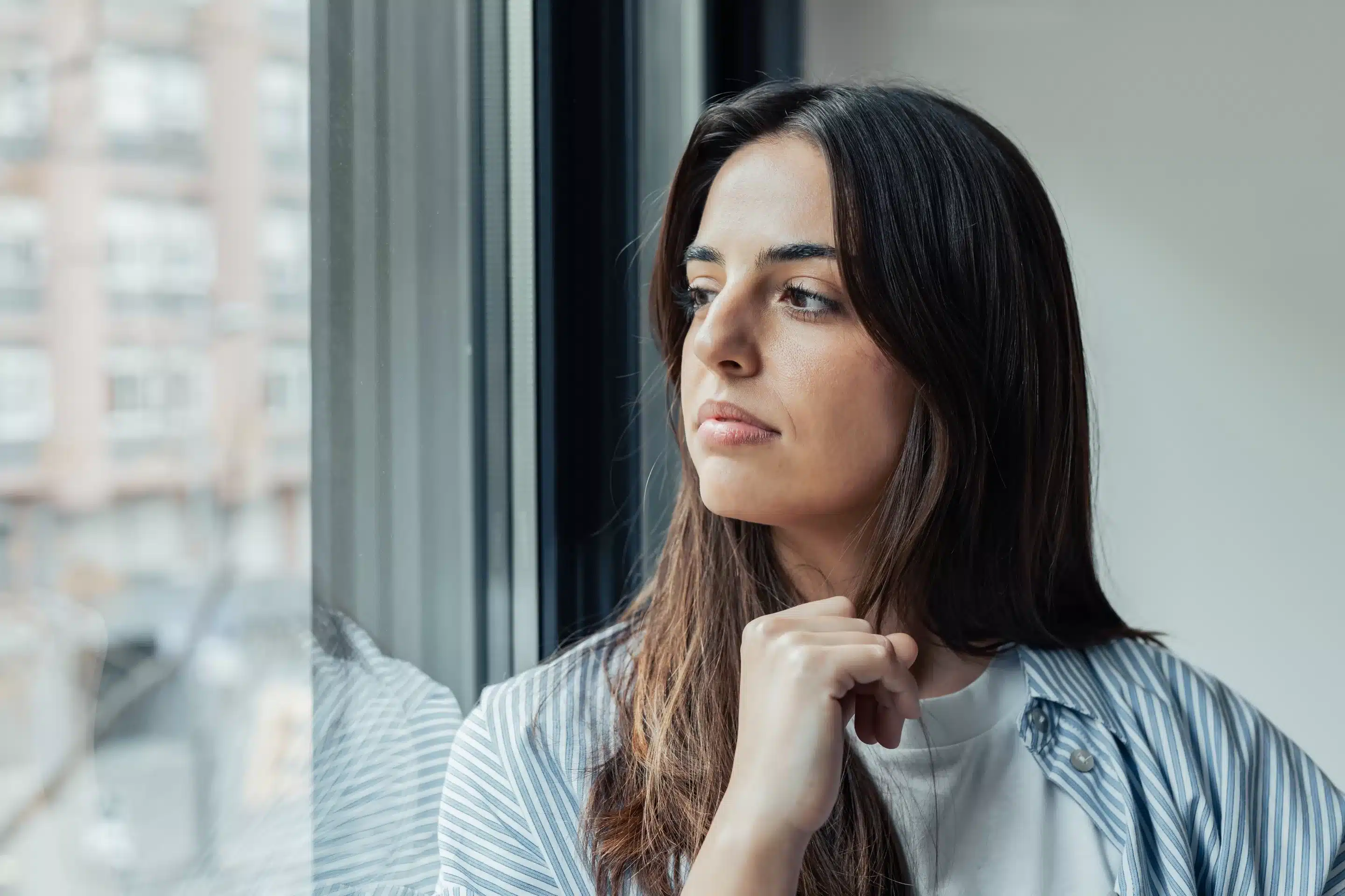 Unhappy thoughts. Worried young caucasian woman look at window
