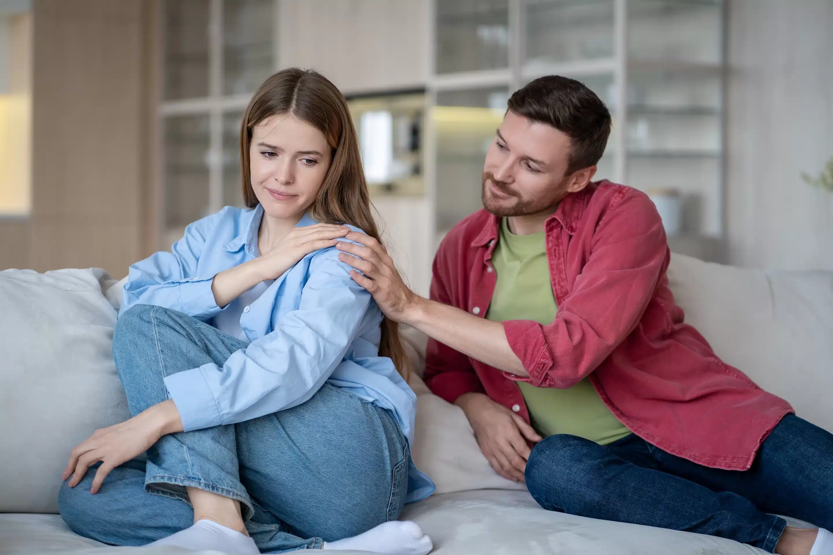 Smiling careful husband calms upset vulnerable wife on home couch, talk after quarrel and peace