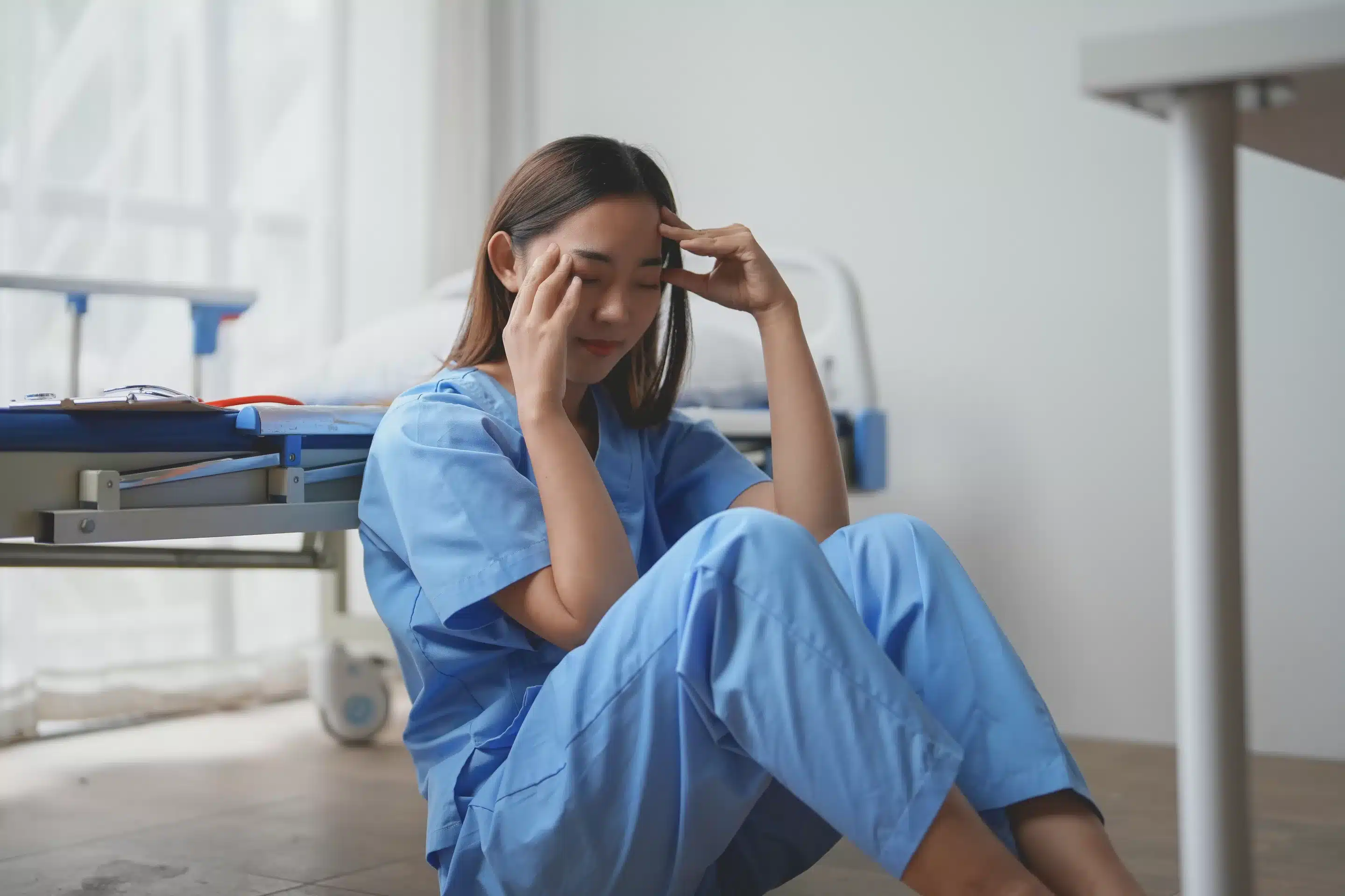 Physician Burnout a woman in blue scrubs sitting on the floor