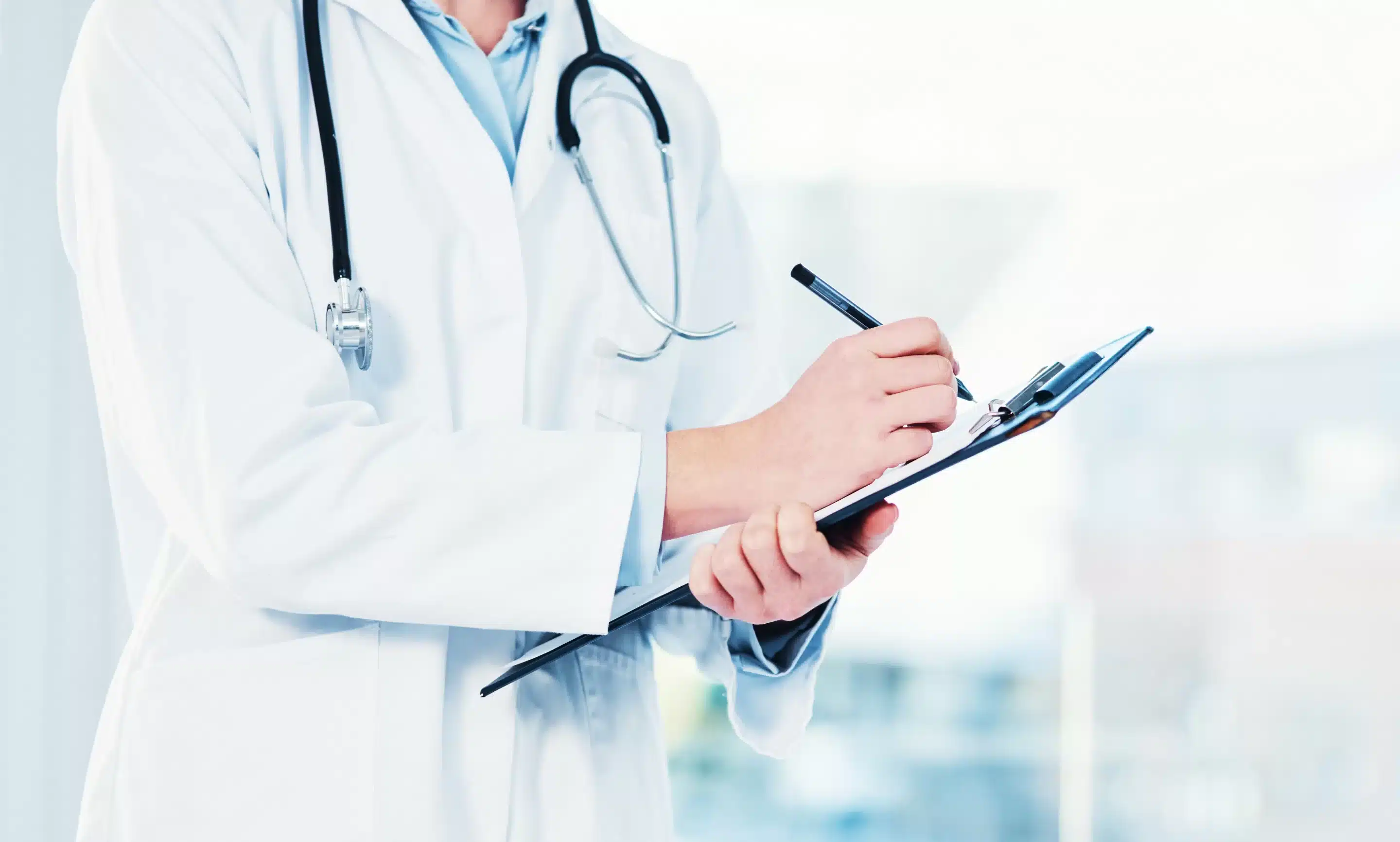 medical professional in a private medical practice filing out a form on a clipboard