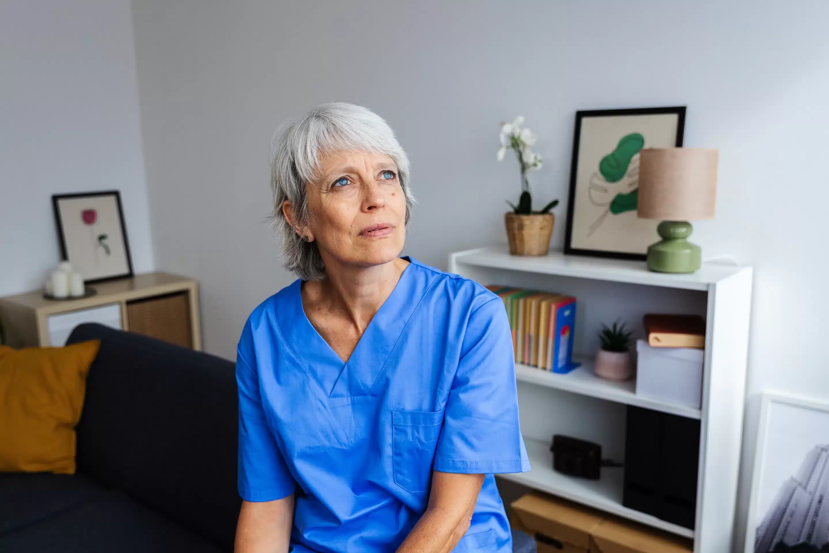 a woman in blue scrubs sitting on a couch