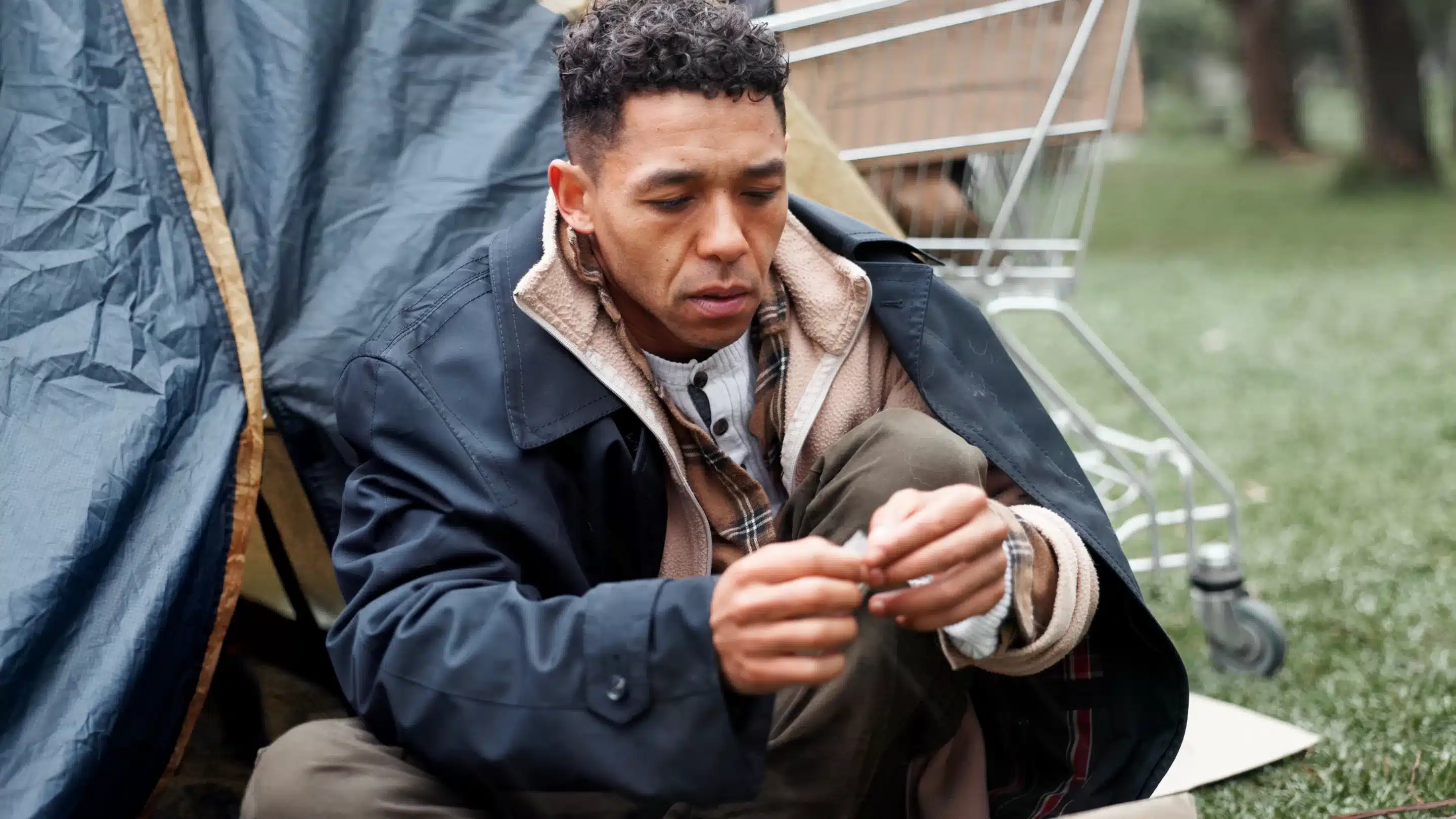 Man, poverty and homeless with drugs at park, package and thinking with illegal product by tent in winter