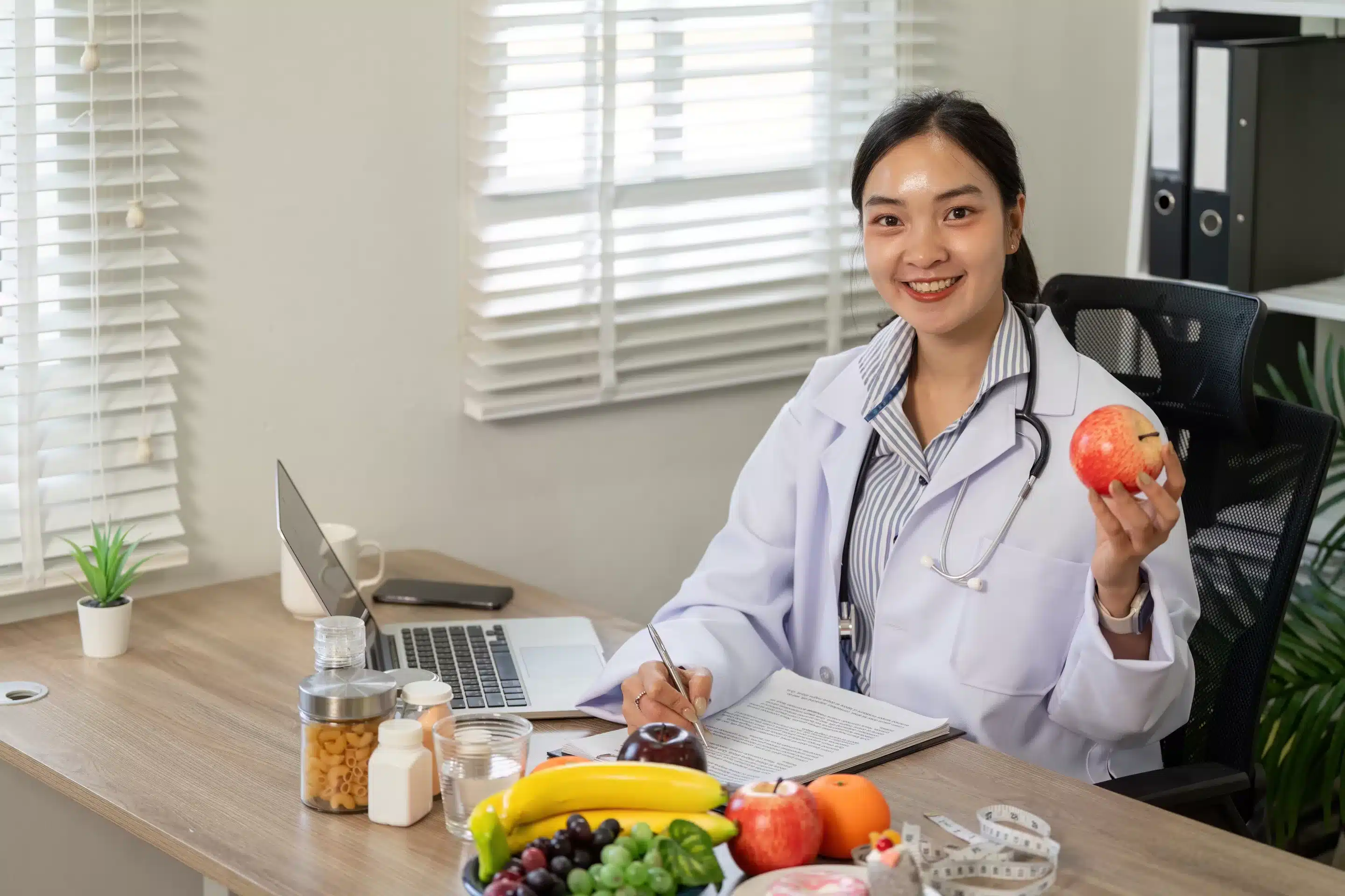 a woman in a white coat holding an apple