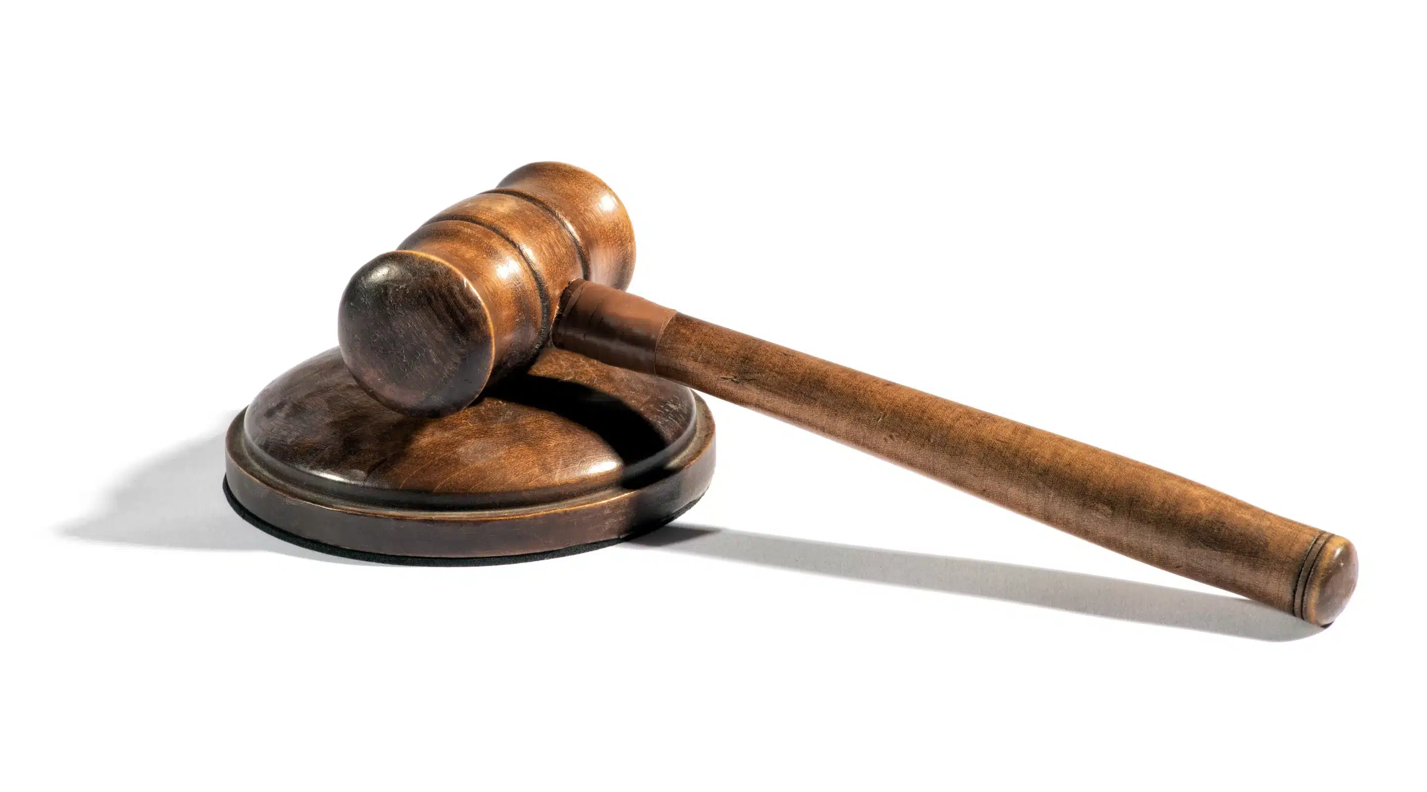 Wooden gavel on a white background with a stark shadow