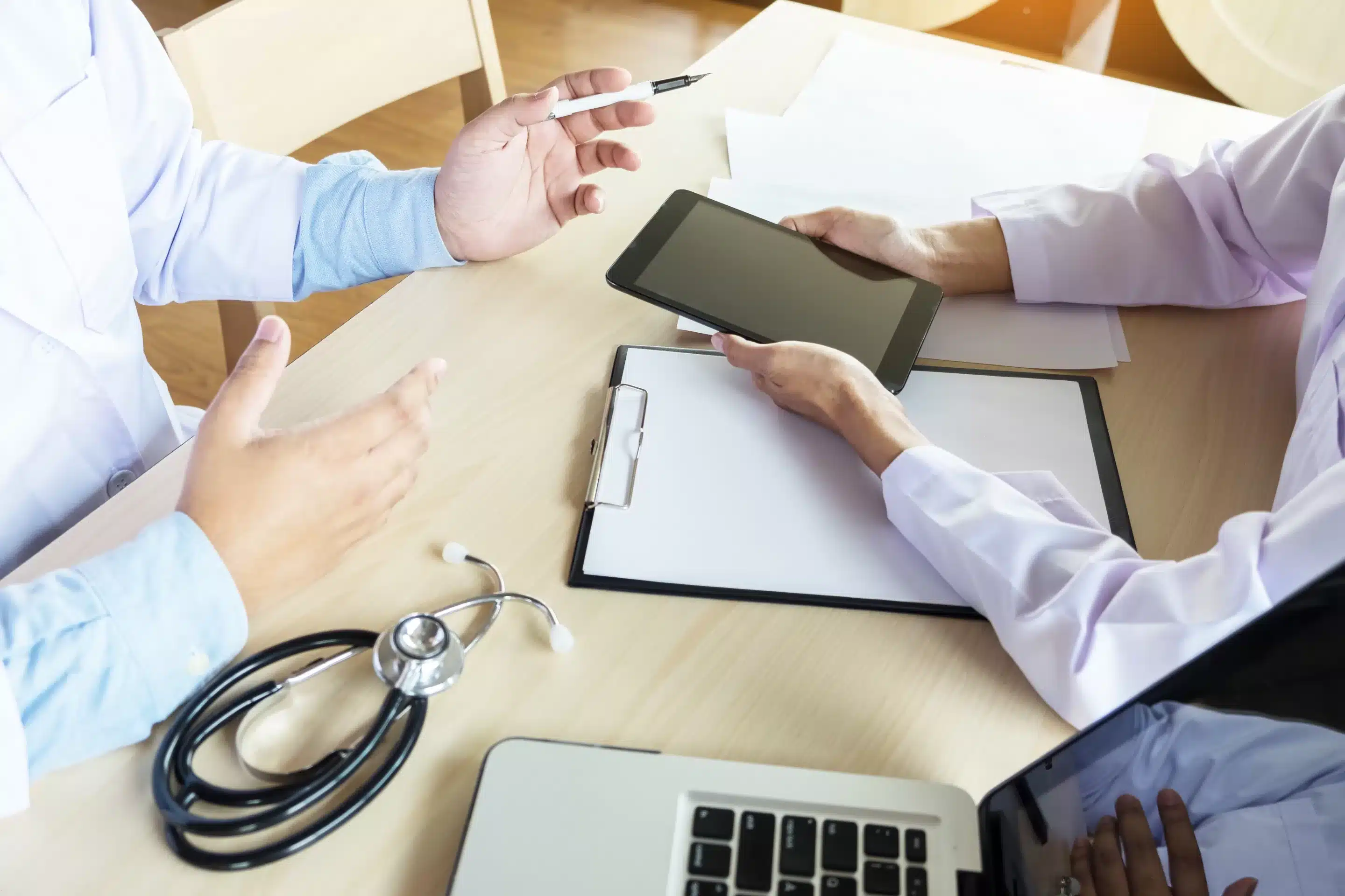 Two doctors discussing patient notes in an office pointing to a clipboard