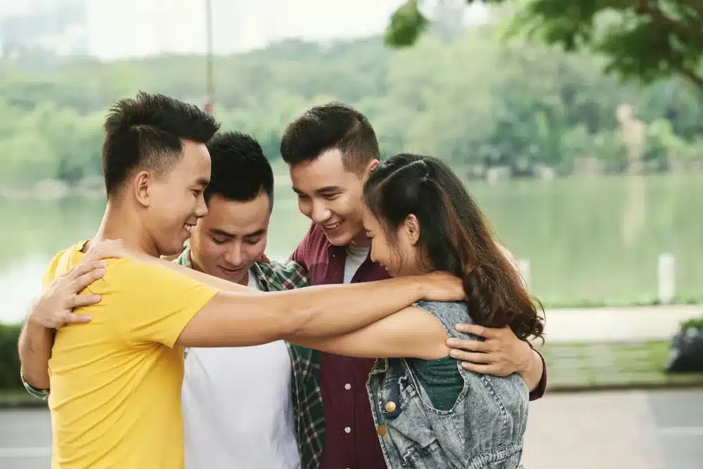 Four teen friends hugging outdoors at the river