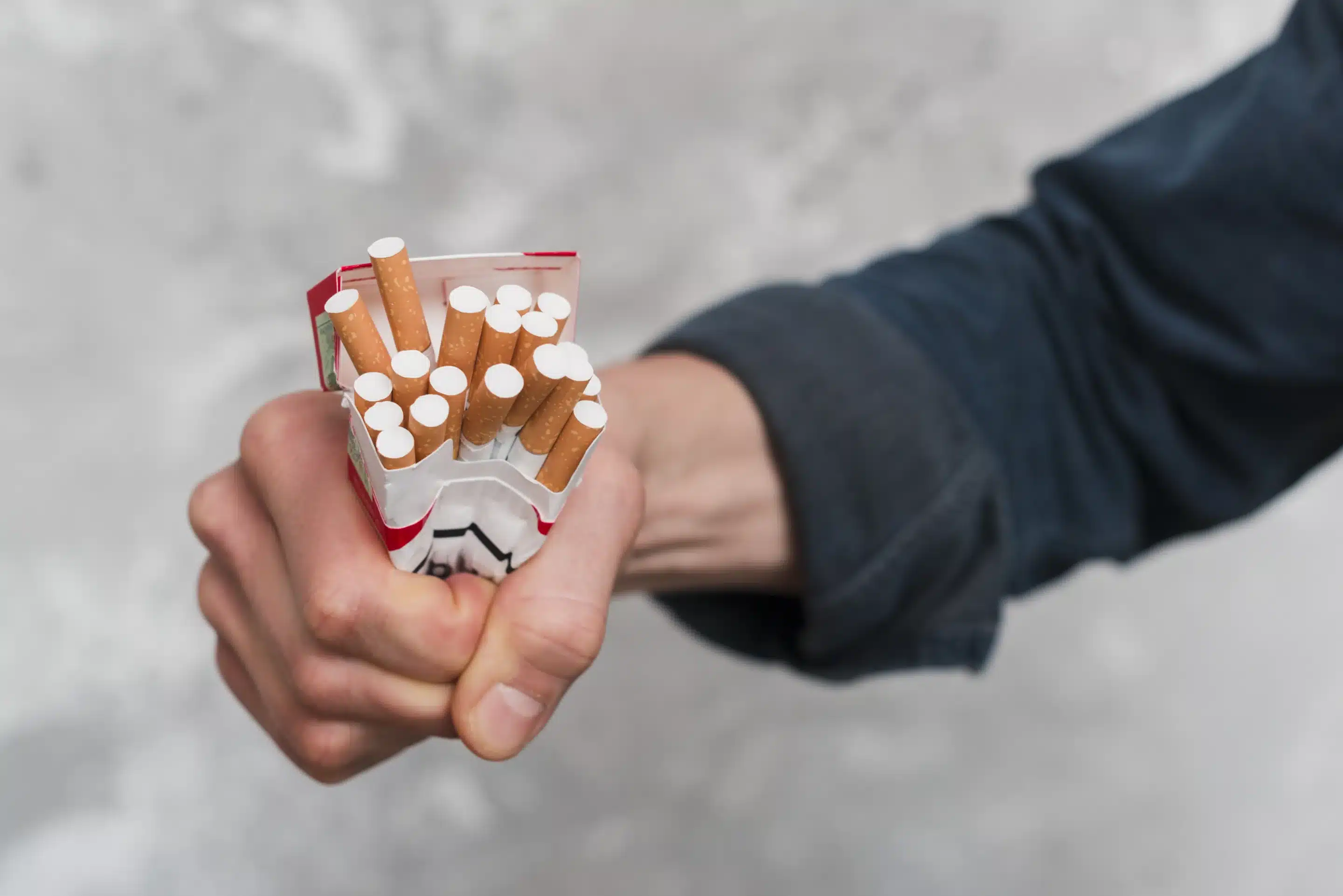Close-up of man's hand crushing cigarettes box
