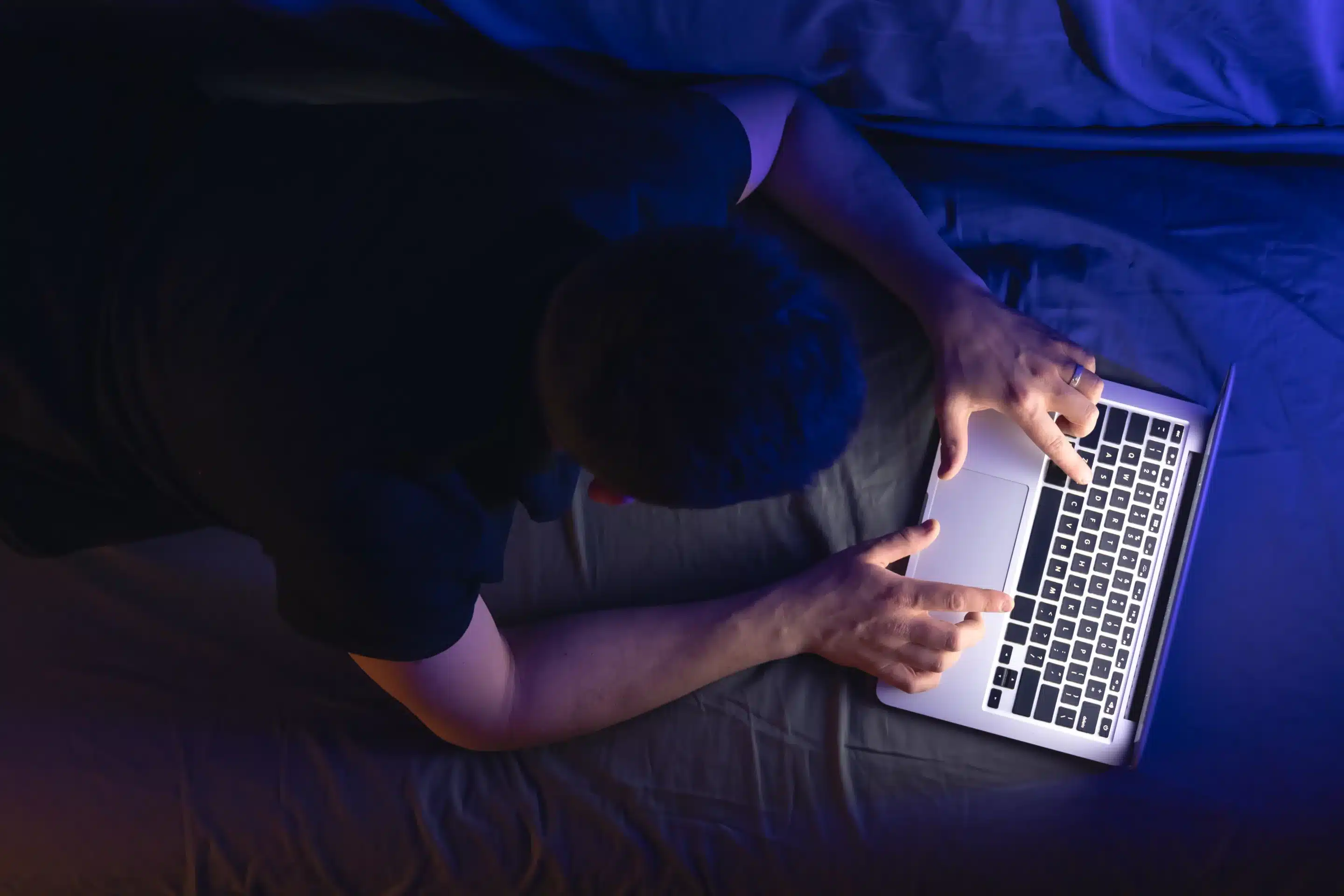 Man lying on his stomach using a laptop, working or browsing comfortably