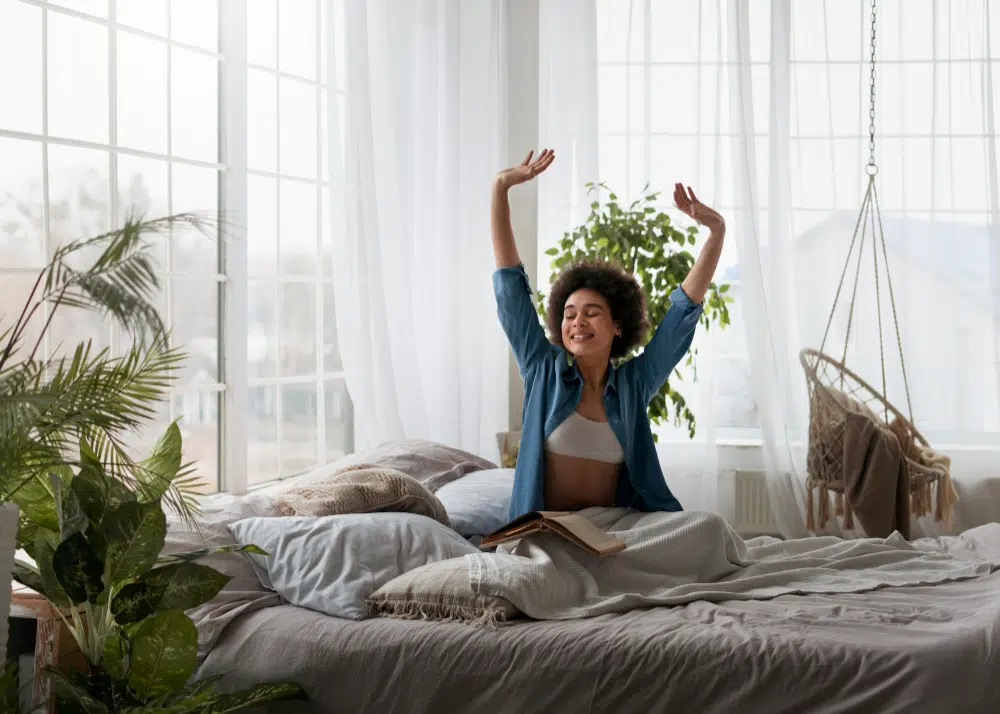 Happy young woman waking up refreshed in a bright, well-decorated bedroom