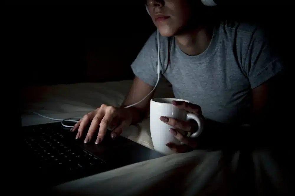 Woman working late at night on her laptop, focused and illuminated by screen light