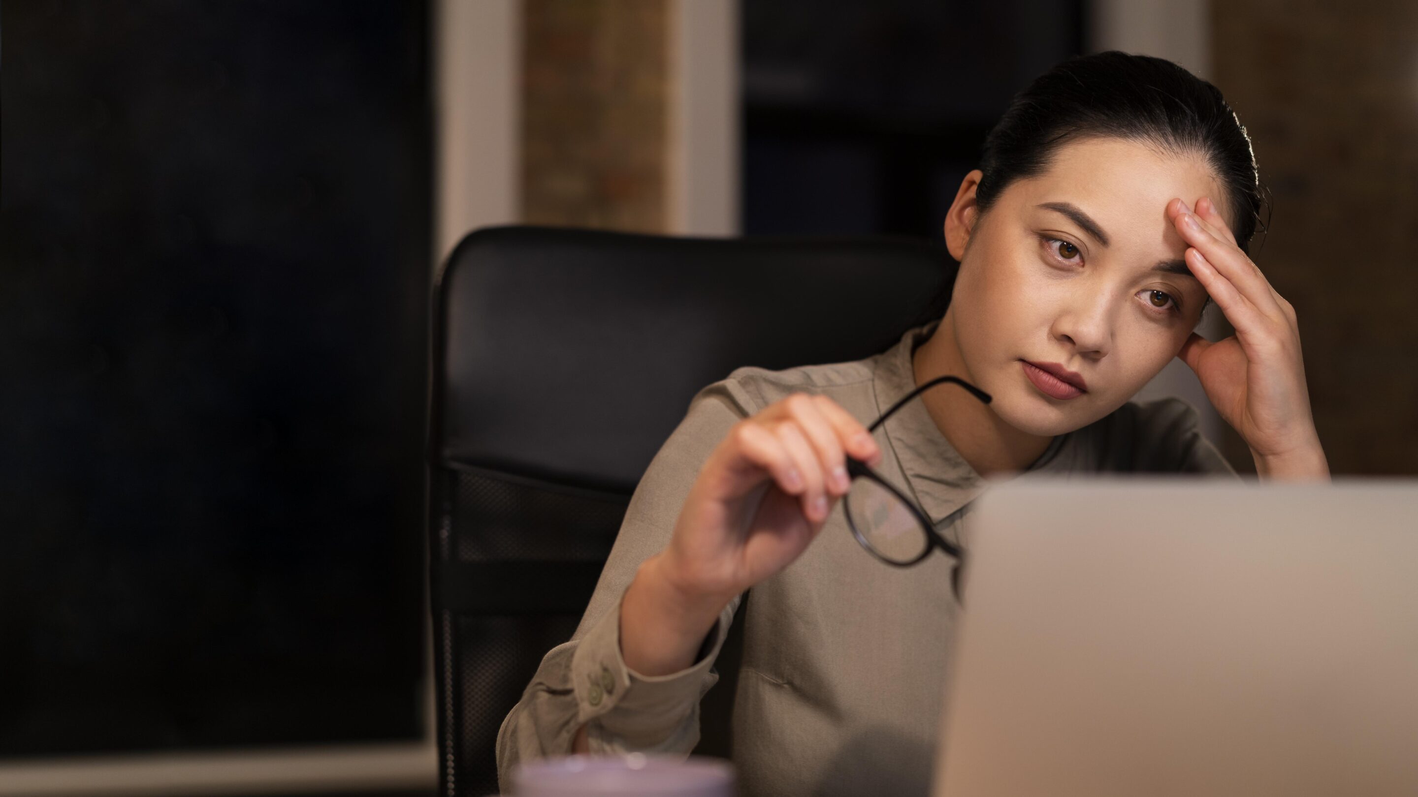 Exhausted woman working late at the office, sitting at her desk with a tired expression
