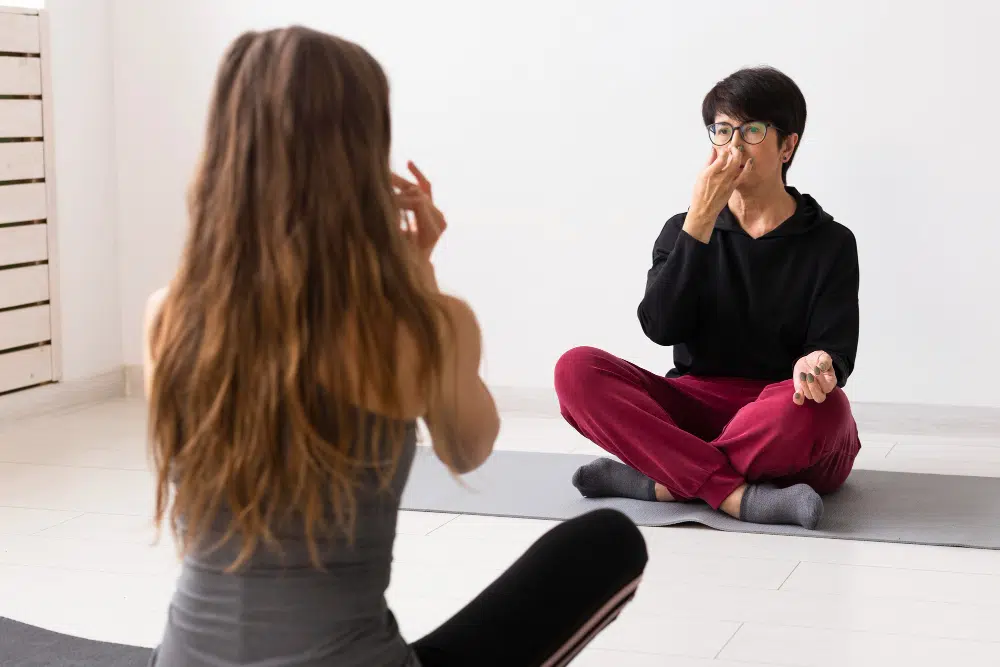 Two women practicing guided breathing therapy while sitting face-to-face<br />
