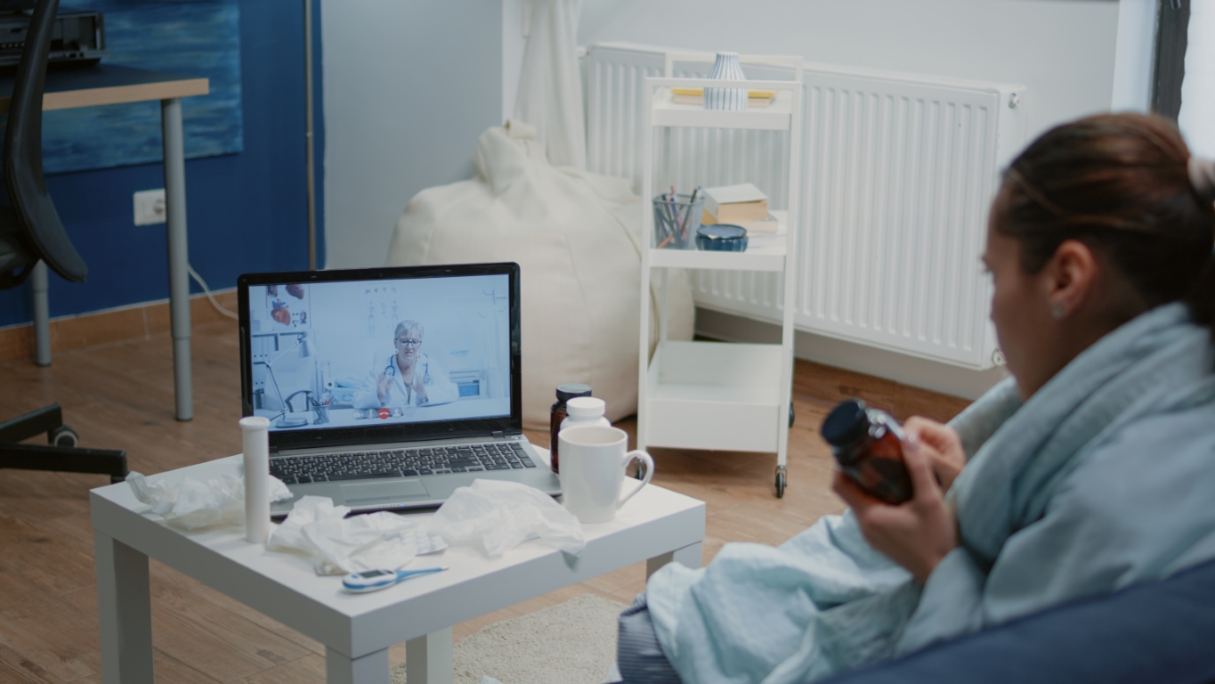Woman with cold and flu using video call for telemedicine Sick woman with cold using video call to consult doctor from home