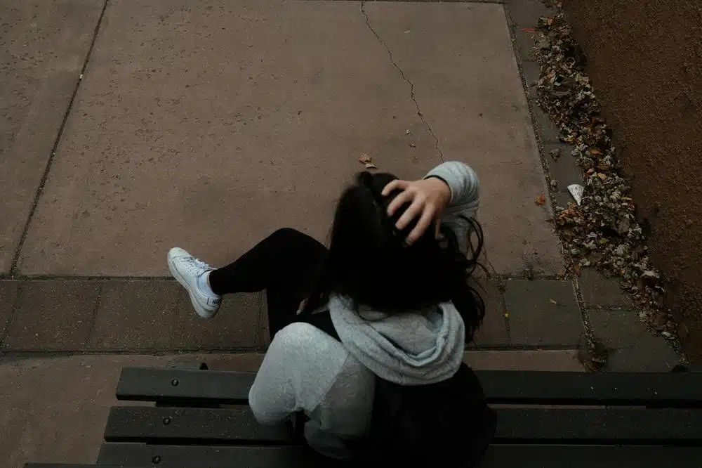 A person sitting on a bench on a sidewalk