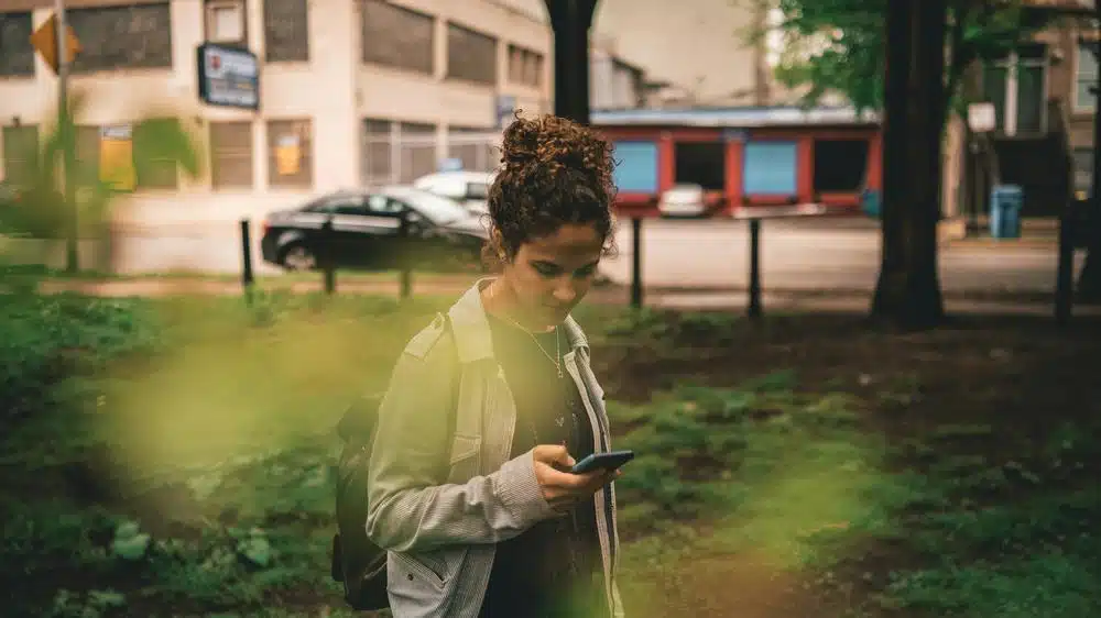 a woman standing in the grass looking at her cell phone - adhd