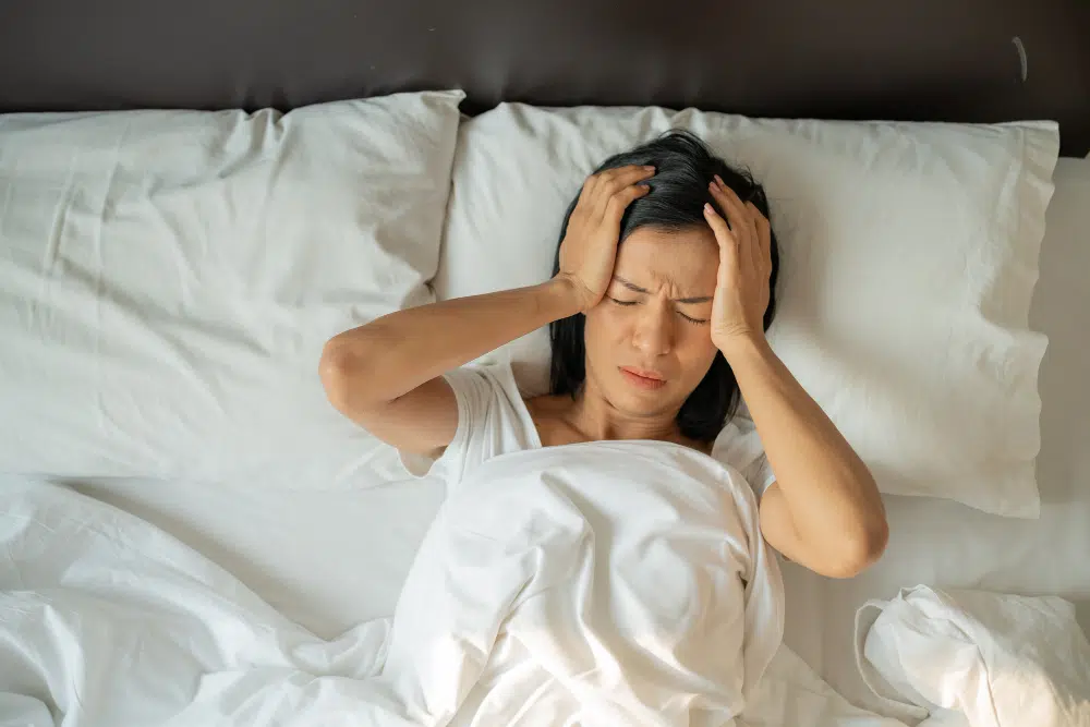 Exhausted middle-aged woman with insomnia lying awake in bed at night