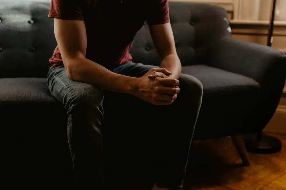 Man sitting on couch with hands clasped